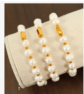 Macro detail of freshwater pearl bracelets with gold rectangle tube spacers on fabric stand