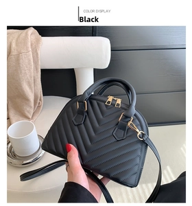 Detail of black chevron quilted handbag with gold dual zippers and detachable strap
