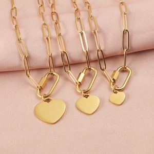 Three sizes of gold heart pendants on paperclip chain necklaces against pink fabric