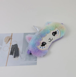 Close-up of rainbow unicorn plush sleep mask featuring soft colorful faux fur and golden horn