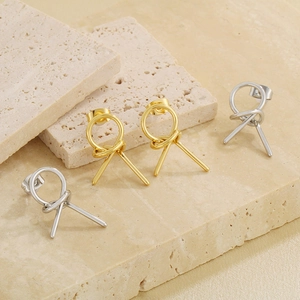Minimalist gold and silver knotted hollow earrings displayed on an elegant stone base