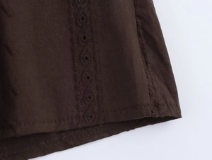 Detailed close-up of dark brown lace embroidery and cutout texture on casual cotton top