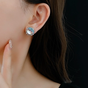 Close-up of sparkling round silver stud earrings with crystals on a female model