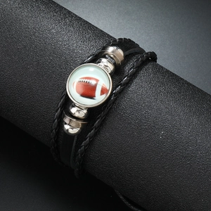 Détail d'un bracelet en cuir tressé noir avec un charm central en verre motif rugby