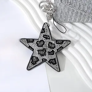 Close-up of star keychain with crystal leopard pattern, metal bell, and ring detail