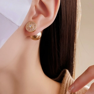 Close-up of elegant gold pearl earrings with sparkling zircon on a female model