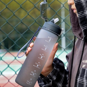 Large grey matte sports bottle with time markers held by a person on a sports field