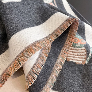 Detailed macro view of woven cat owl pattern and fringe edges on a thick cashmere scarf