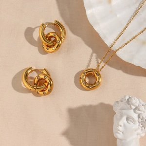 Detail view of 18K gold plated jewelry set with sparkling zircon donuts on textured fabric