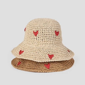 Detailed macro view of crochet straw hat texture with embroidered 3D red heart patterns
