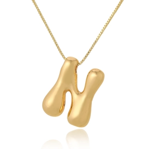 Polished gold letter N pendant on a delicate chain necklace over a white background