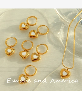 Detailed view of golden heart jewelry set with white shell inlay on a glass plate