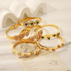 Detail of 18K gold titanium bracelets with colorful heart zircon and white shell inlays