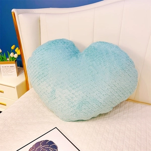 Détail d'un coussin en peluche bleu clair en forme de cœur avec texture de fourrure douce