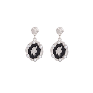 Détail des boucles d'oreilles argentées avec centre noir et finitions en perles