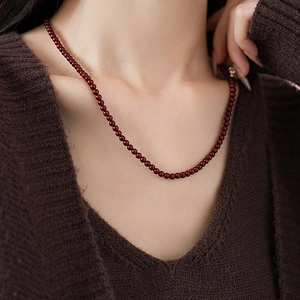 Close-up of deep red bead necklace on model with vintage stainless steel beads