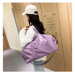 Purple waterproof travel bag with shoulder strap shown on model in a hallway