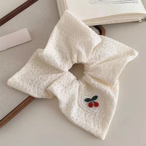 Sweet cream lace scrunchie with embroidered cherries and heart trim on a wooden tray
