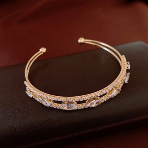 Close-up of gold double-layer open bangle featuring marquise cut crystal and micro pavé