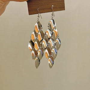 Détail de boucles d'oreilles à paillettes argentées avec design en écailles de métal poli