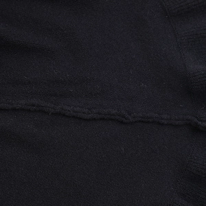 Primer plano del tejido de punto negro con costuras finas y detalles de dobladillo