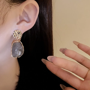 Detail of irregular grey marble pendant earring with gold-toned textured metal finish