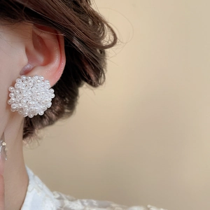Primo piano di eleganti orecchini a lobo con fiori di perle bianche indossati da modella