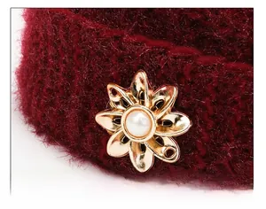 Detailed macro view of burgundy knit fabric with elegant gold flower and pearl buckle