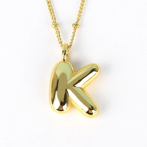 Detailed view of polished 3D initial K pendant in gold finish on a delicate chain