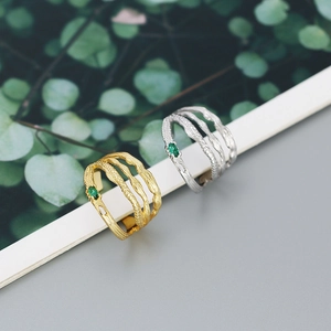 Close-up of double-layer irregular silver rings with green marquise zircon and bark texture