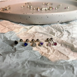 Macro shot of six heart-shaped zircon stud earrings in various colors for cartilage piercing
