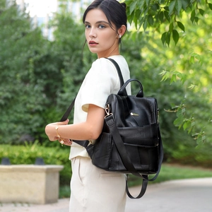 Detail of black quilted leather backpack showing stitched grid texture and metal hardware
