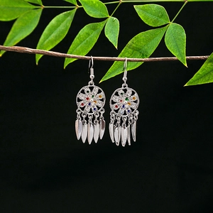 Detail of bohemian dreamcatcher earrings with colorful beads and metal leaf tassels