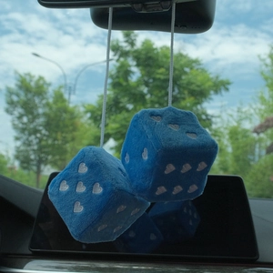 Blue plush car dice with white heart patterns hanging from a rearview mirror