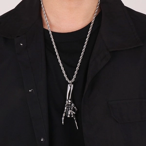 Detail of silver stainless steel skeleton hand pendant on a twisted chain necklace