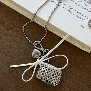 Close-up of heart and woven bag pendants with white bow on a silver beaded chain