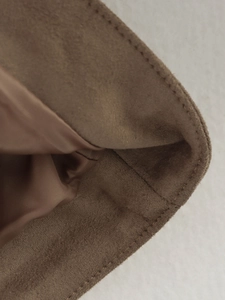 Macro view of brown suede jacket showing detailed stitching and silky lining texture