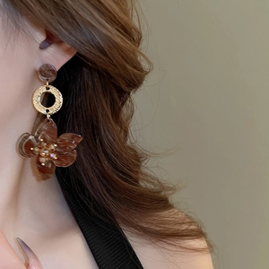 Detailed close-up of retro acetate flower earrings with gold rings and crystals on model