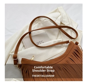 Detail view of brown suede shoulder bag with dense fringe accents and golden metal buckle