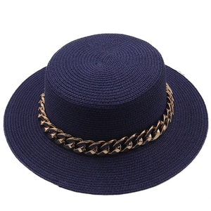 Detail of navy blue straw boater hat featuring a stylish chunky gold chain decoration