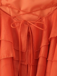 Détails macro d'une robe en mousseline orange avec lacets et volants superposés