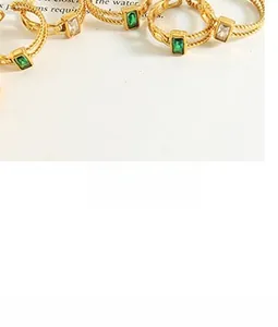 Close-up of twisted rope-style gold ring featuring rectangle emerald and zircon stones