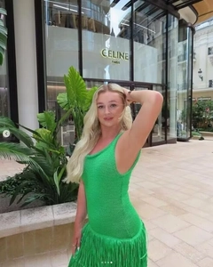 Détail de robe en maille verte avec de longues franges superposées sur l'ourlet