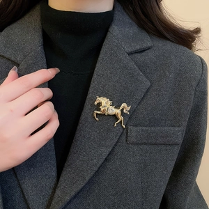 Macro detail of golden horse brooch with crystal inlay pinned on a grey suit lapel