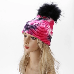 Detail view of tie-dye knit beanie featuring a large faux fur pom-pom on top