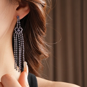 Gros plan de boucles d'oreilles à pampilles en strass violets portées par un mannequin