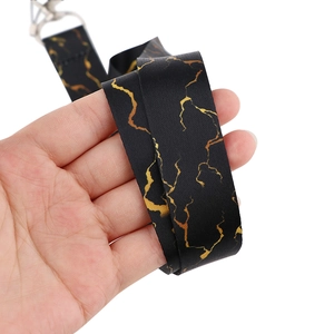 Detailed view of black fabric lanyard featuring elegant golden marble texture and metal clip