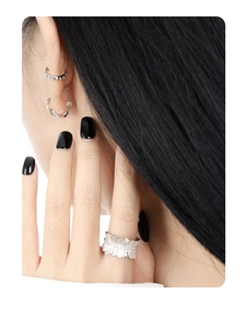 Close-up of geometric gear earrings and ring on model with minimalist silver finish