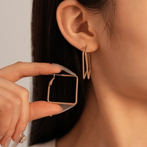 Close-up of minimalist matte beige geometric square hoop earrings worn by a model