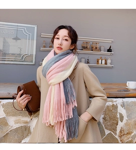 Detail of soft thick knitted tassel scarf in pink, gray, and beige color block patterns